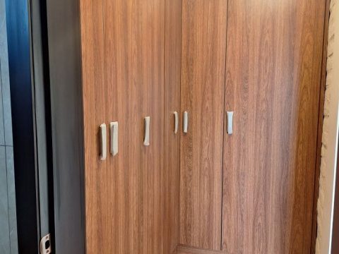 Closet empotrado en L de piso a techo con puertas abatibles en acabado madera