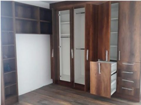 Closet en madera oscura con repisas abiertas, colgadores y cajonera