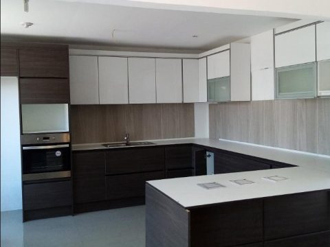 Cocina en U con muebles altos blancos, muebles bajos en wengué y torre de horno
