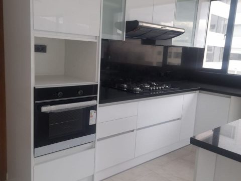 Cocina blanca brillante con torre de horno y mesón de granito negro
