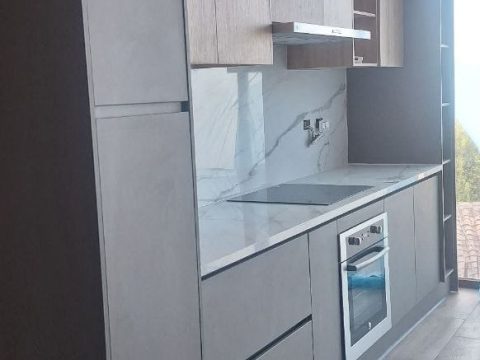 Cocina lineal con columnas en gris, muebles altos en roble y mesón de mármol