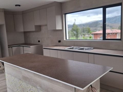 Cocina en tonos arena con isla revestida y ventanal