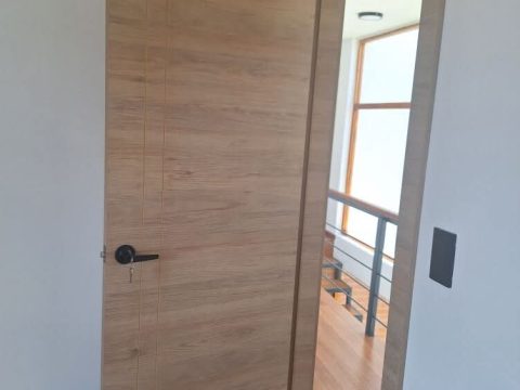 Puerta interior en roble claro con manija negra y marco a juego