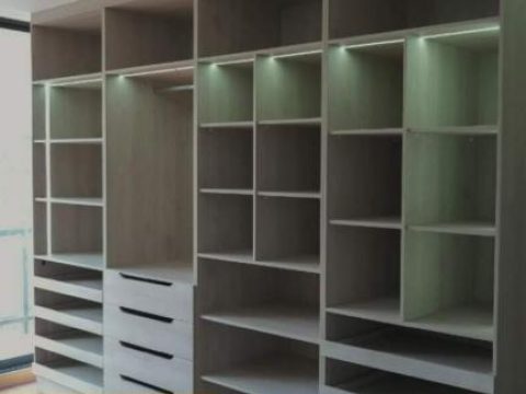 Vestidor de piso a techo con repisas iluminadas y cajoneras