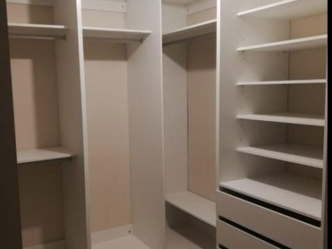 Walk-in closet blanco con colgadores, repisas y cajonera
